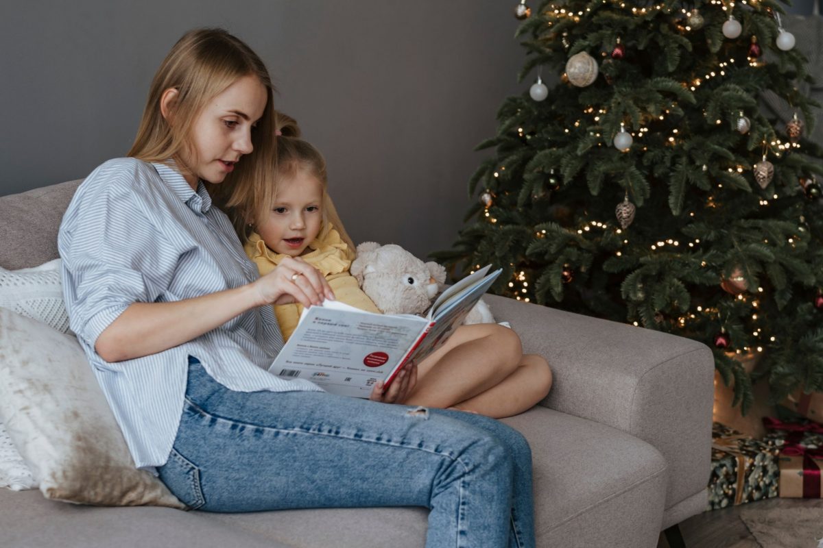 babysitter reading to a child next to Christmas tree
